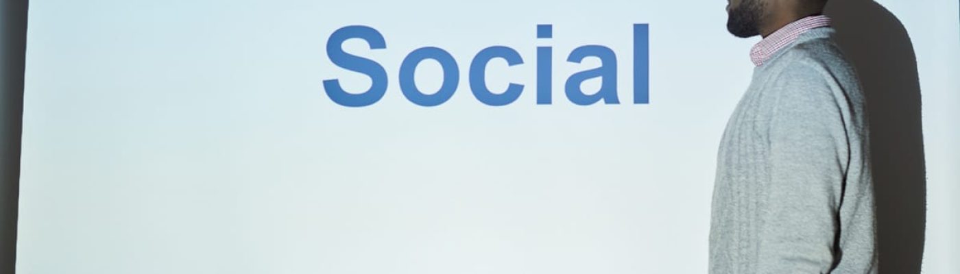 Pensive young Black SMM specialist in sweater standing at projection screen and explaining marketing plan at training class